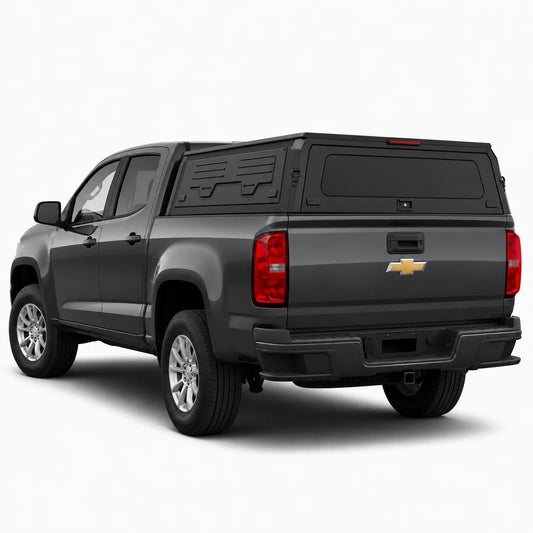 A dark gray Chevrolet pickup truck with a black hardtop canopy over the bed, shown from a rear three-quarter angle on a light gray studio background.
