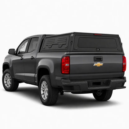 A dark gray Chevrolet pickup truck with a black hardtop canopy over the bed, shown from a rear three-quarter angle on a light gray studio background.