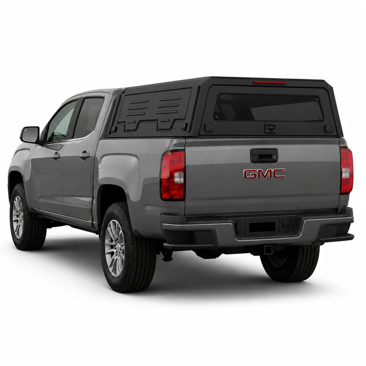 A gray GMC pickup truck shown from a rear three-quarter angle, fitted with a black hardtop canopy over the bed, on a clean white background.