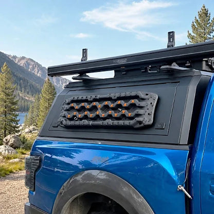 Aluminum overland truck cap with exterior MOLLE panel and recovery boards mounted on the side