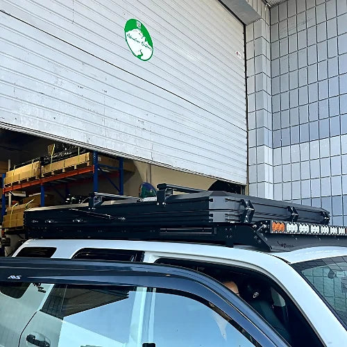 Urban rooftop bar installation with rooftop tent on white SUV in front of garage