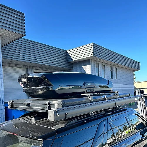 Black roof cargo box mounted on crossbars over rooftop tent