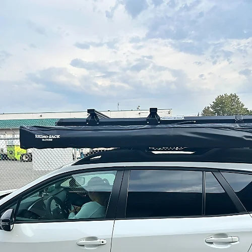 Rooftop tent with mounted roof bars and awning installed on a crossover SUV