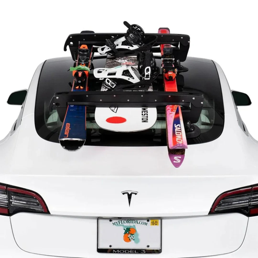 Ski rack mounted on a white car roof holding ski equipment.