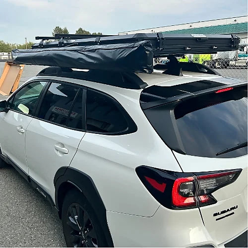 Subaru Outback with mounted rooftop bars and retractable awning system for outdoor travel