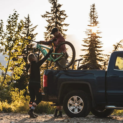 Man standing on his truck and lifting two bikes out of Swagman Paramount Tailgate Pad. He is reaching them to a women