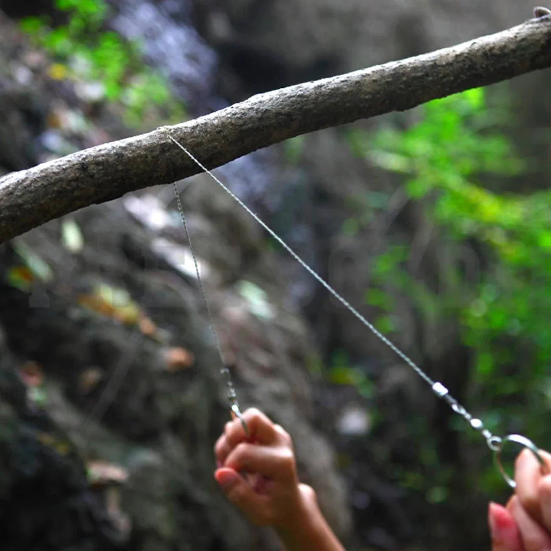 Hands using AO tactical wire saw to cut a tree branch outdoors in a forest setting