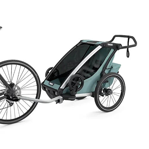 Thule Chariot Cross Single Alaska Blue connected to a bicycle using tow arm for family biking adventures