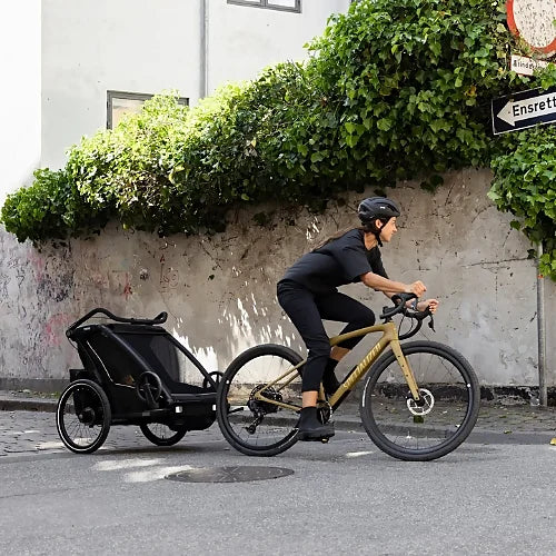 Thule Chariot Sport 2 connected to bicycle during urban ride, demonstrating safe child transport with aerodynamic design