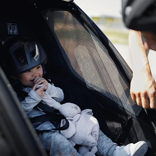 Child seated inside Thule Chariot Sport Single with helmet and mesh window ventilation