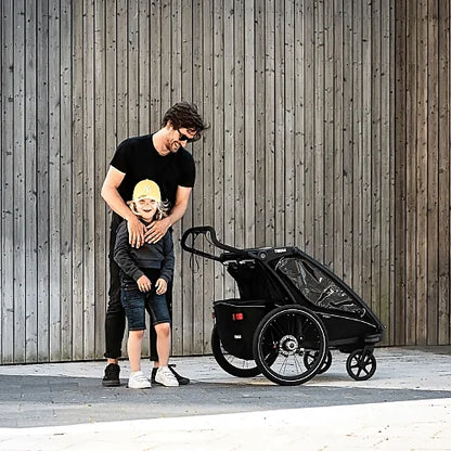 Parent with child using Thule Chariot Sport Single stroller outdoors on paved surface