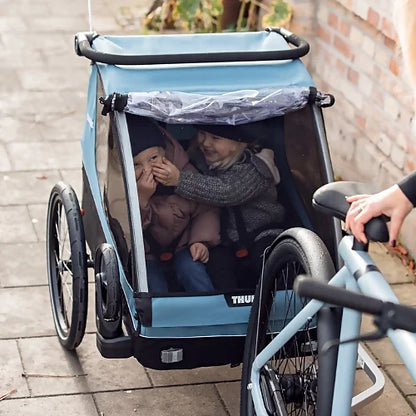 Thule Courier bike trailer with two kids seated inside during a ride