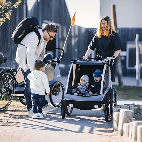 Family using Thule Courier in stroller mode with two kids inside