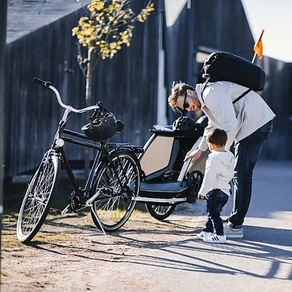 Father preparing Thule Courier bike trailer with child on sidewalk