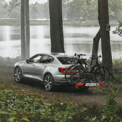 Sedan with Thule Epos hitch bike rack carrying two bikes in scenic forest setting