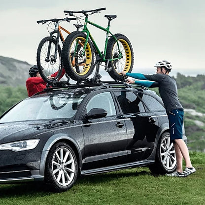 Riders mounting fat bikes with Thule straps on roof rack setup in rugged terrain