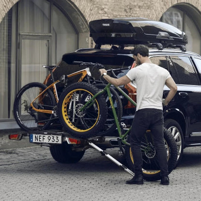 Person rolling fat bike onto car rack using ramp