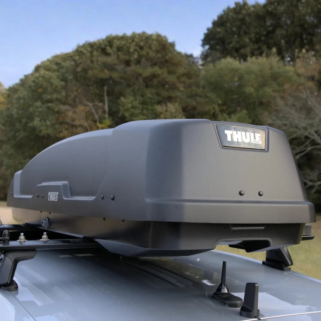 Thule force xt sport roof box mounted on a vehicle with a trees in the background