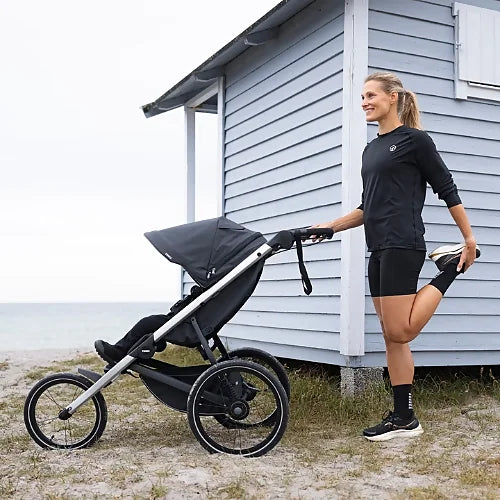 Thule Glide 3 jogging stroller folded compactly with one hand for easy transportation and storage