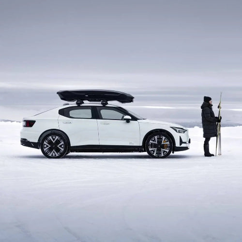 Thule Motion 3 Low XL aerodynamic roof box on white car in snowy landscape, perfect for ski and winter adventures