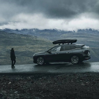Thule Motion 3 Low XXL cargo roof box mounted on SUV during mountain road trip, aerodynamic and weather-ready design