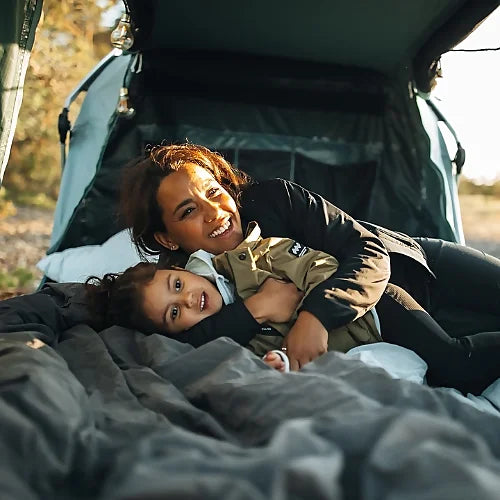 Cozy interior view of Thule Outset Hitch Car Tent with mother and child relaxing on comfortable mattress.
