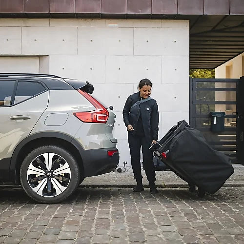 Woman rolling folded Thule Outset Hitch Car Tent for easy transport and storage before setup