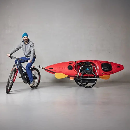 Thule Reacha Sport bike trailer transporting red kayak attached to bicycle, highlighting carrying capacity for sports equipment