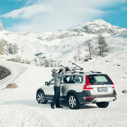 women standing next to a Volvo in the snow and putting her skis into the Thule SnowPack