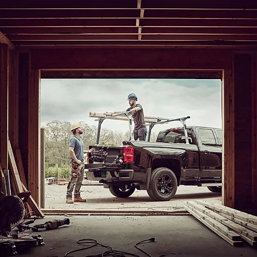 Workers loading lumber onto Thule TracRac Pro 2 truck rack at construction site
