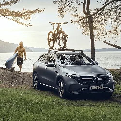Thule UpRide bike rack mounted on Mercedes EQC with two bikes by a lakeside