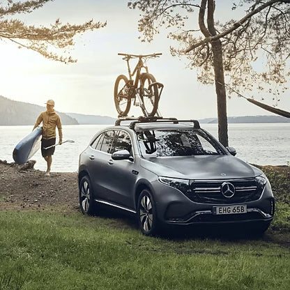 Thule UpRide bike rack mounted on Mercedes EQC with two bikes by a lakeside