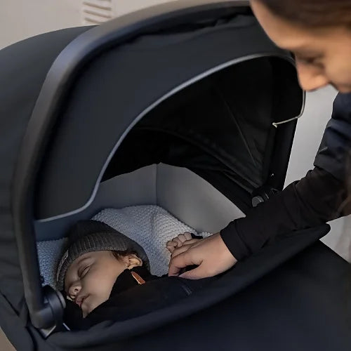 Close-up of sleeping baby inside Thule Urban Glide 3 bassinet with canopy partially open