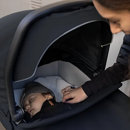 Close-up of sleeping baby inside Thule Urban Glide 3 bassinet with canopy partially open