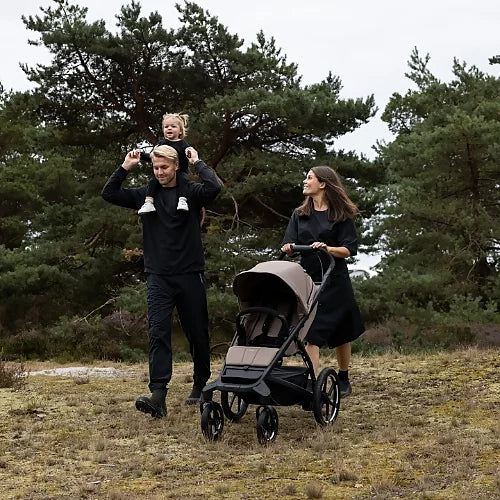 Family hiking with the Thule Urban Glide 4-Wheel all-terrain stroller in tinted taupe on rugged outdoor trail
