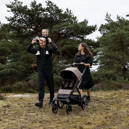 Family hiking with the Thule Urban Glide 4-Wheel all-terrain stroller in tinted taupe on rugged outdoor trail