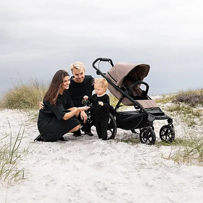 Thule Urban Glide 4-wheel tinted taupe all-terrain stroller with family on the beach