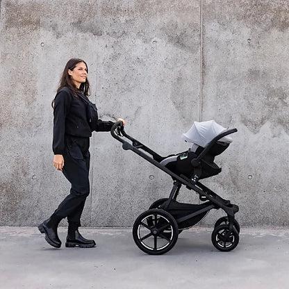 Thule Urban Glide 4-wheel stroller used as travel system with infant car seat adapter on city sidewalk