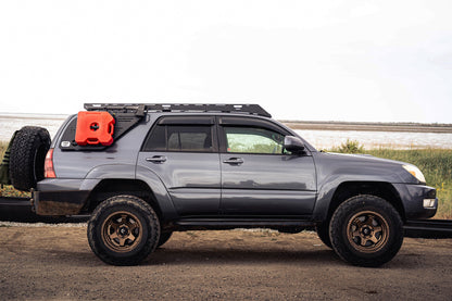 Gray SUV with van44 platform roof racks and off-road tires and equipment on a dirt road
