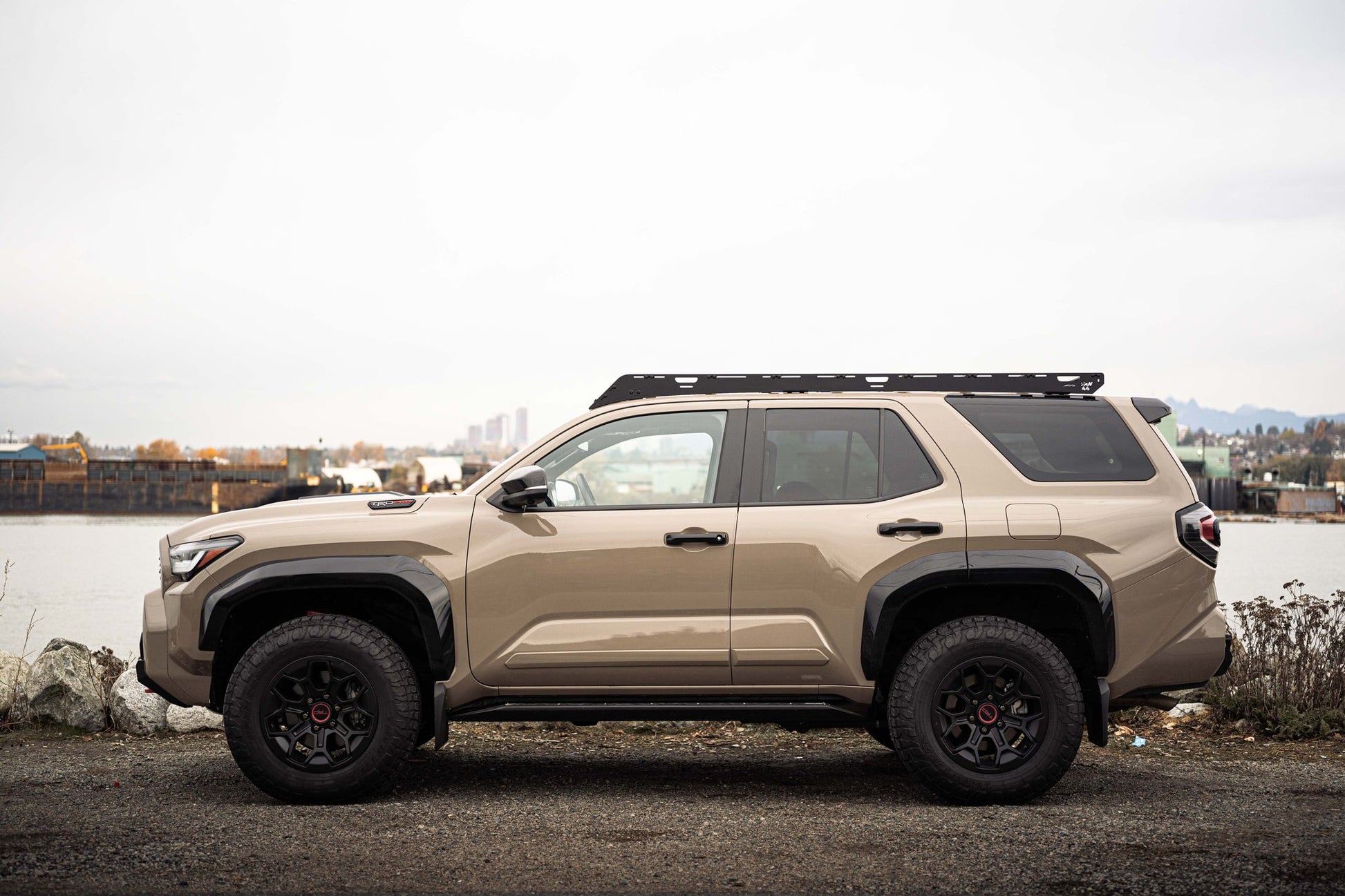 Beige Toyota 4runner with platform roof rack parked near a body of water