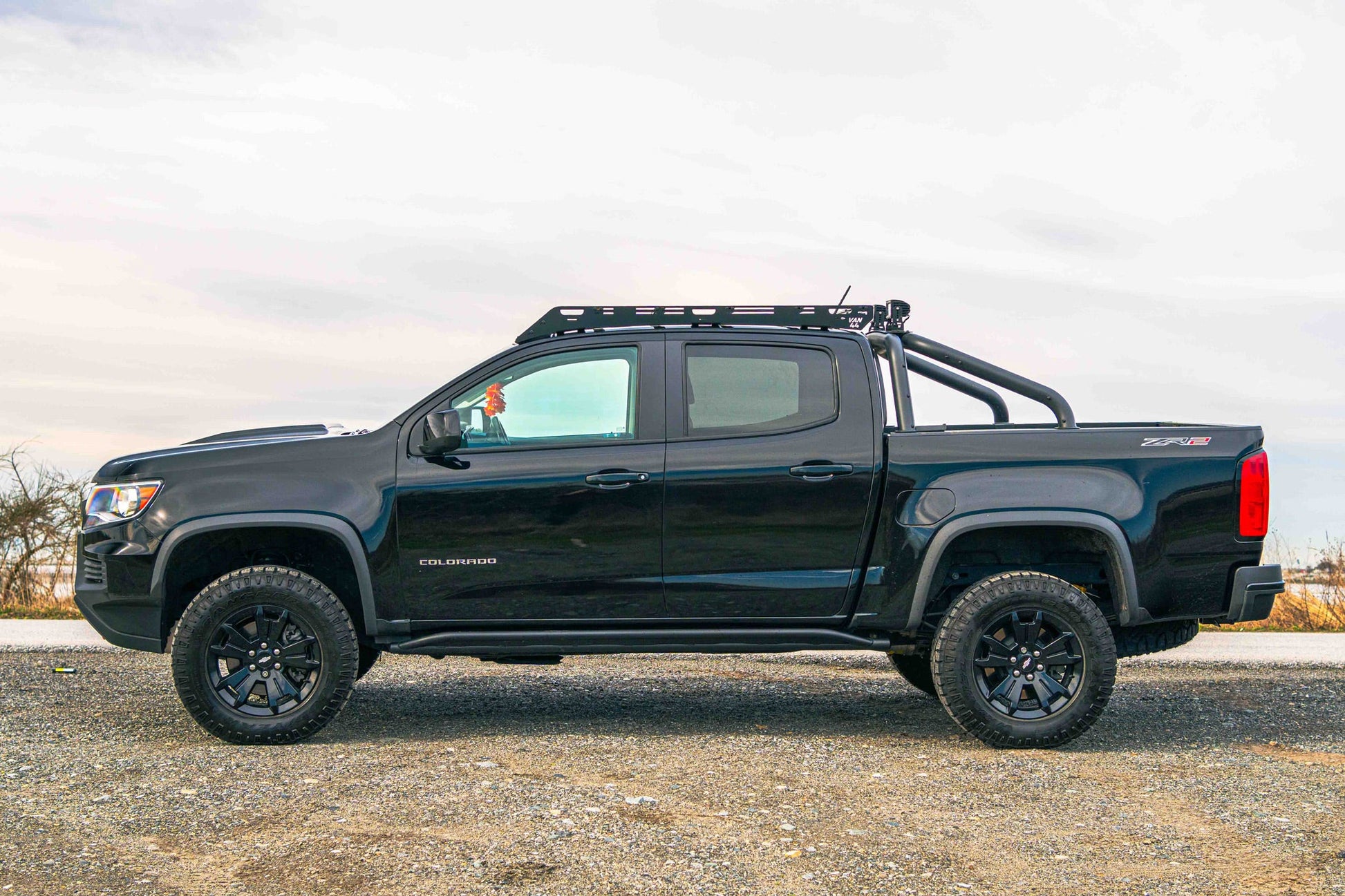Black Chevrolet Colorado ZR2 truck with Van44 platform roof rack on a gravel surface