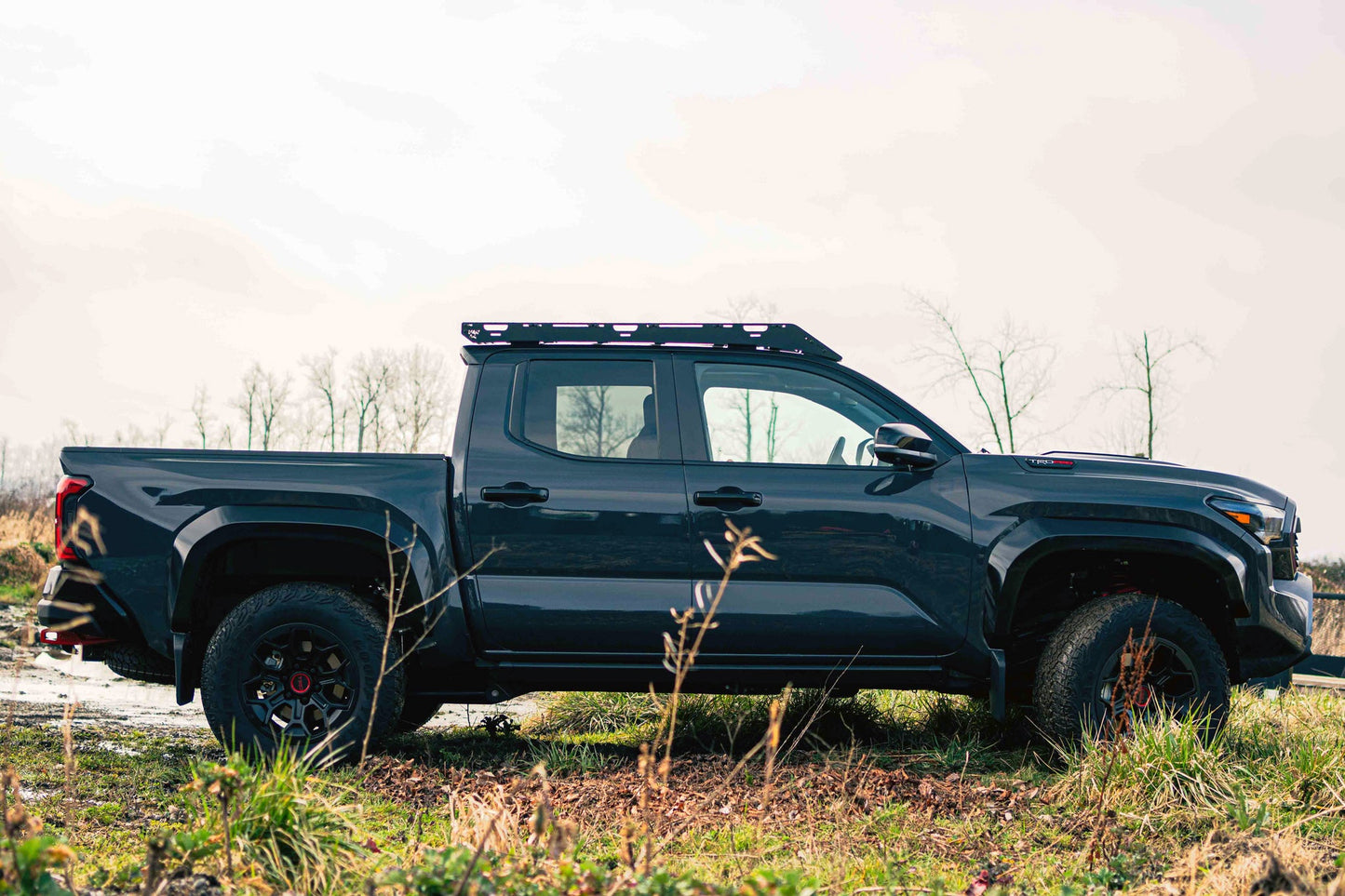 Black pickup truck on a dirt road with a van44 roof rack platform under clear sky background