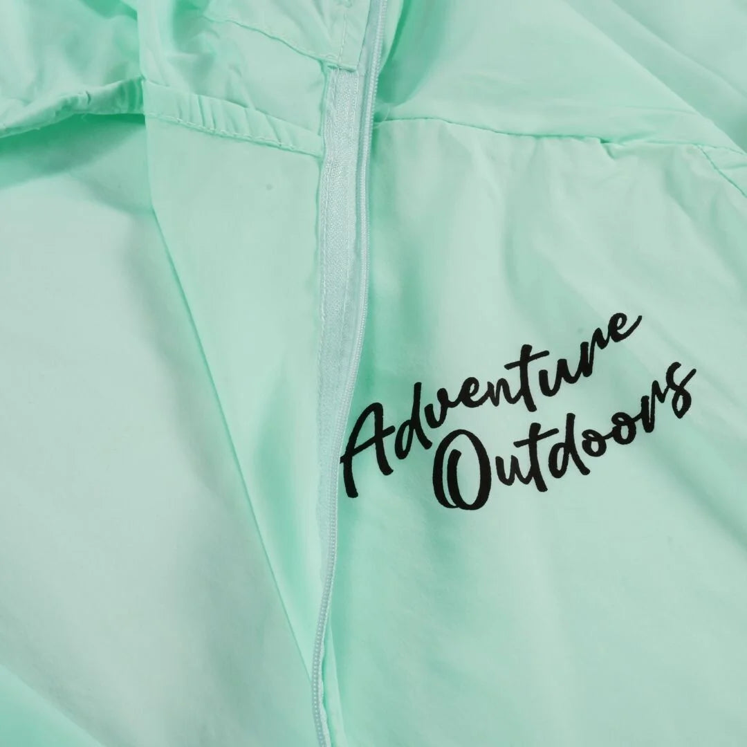 Close-up of Adventure Outdoors logo on teal windbreaker chest area
