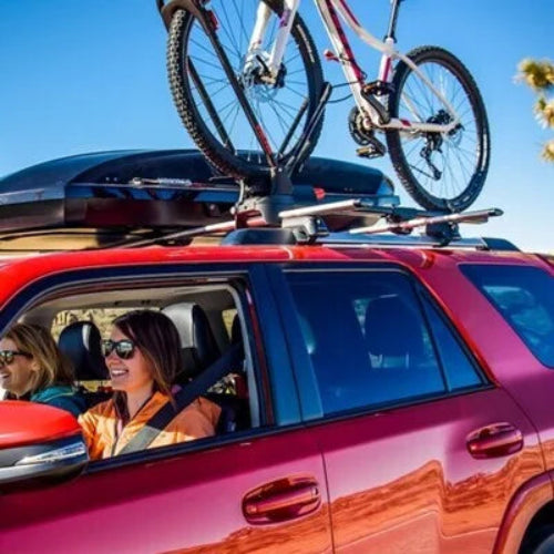 Yakima JetStream crossbars carrying bike and cargo box on red SUV in adventure setting