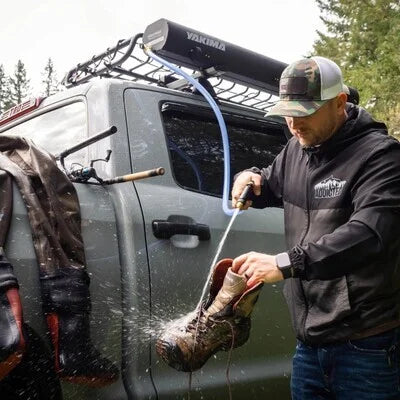 Yakima RoadShower mounted on roof rack providing pressurized water to clean muddy boots and outdoor gear