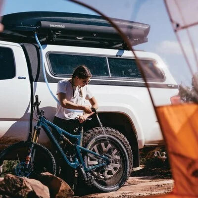 Yakima RoadShower mounted on truck roof being used to rinse a mountain bike at a campsite