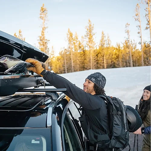 Yakima SkyBox NX Skinny roof box being loaded with skis using dual-side access