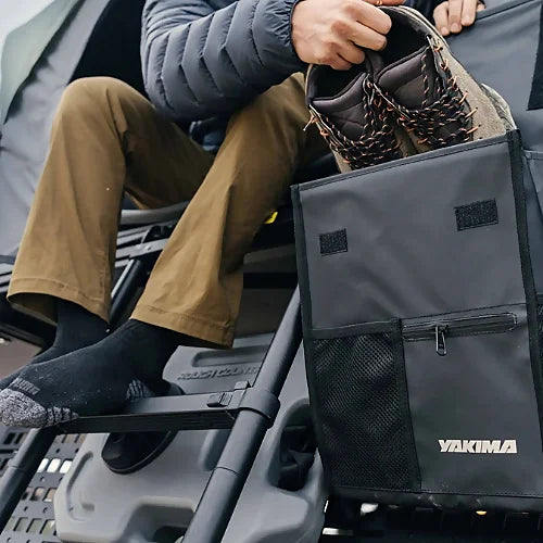 Close-up of Yakima SkyPeak HD accessory shoe bag in use with hiker holding boots