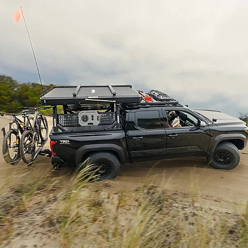 Fully loaded overland rig with Yakima SkyPeak HD Rooftop Tent and bikes, riding on beach sand