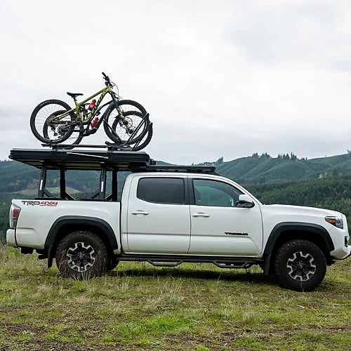 Side view of white Toyota Tacoma with Yakima SkyPeak HD tent and bike on top